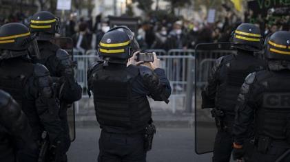 A French riot police officer photographs protesters with his phone during a demo<em></em>nstration in Marseille, southern France, Saturday, Nov. 21, 2020.