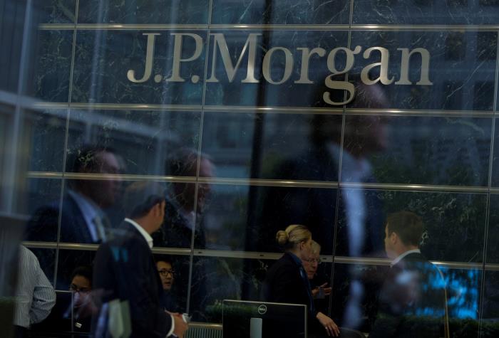 Workers are reflected in the windows of the Canary Wharf offices of JP Morgan in Lo<em></em>ndon September 19, 2013. REUTERS/Neil Hall