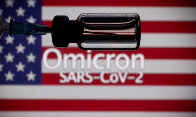 A vial and a syringe are seen in front of a displayed United States' flag and words 