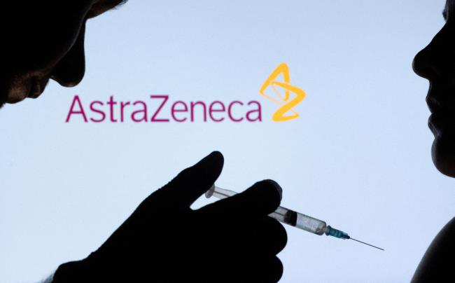 People pose with a needle in front of displayed AstraZeneca logo in this illustration taken December 11, 2021. REUTERS/Dado Ruvic/Illustration