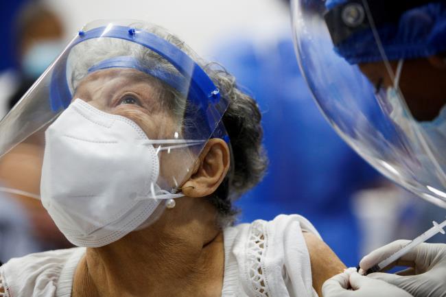 A woman reacts as she receives the first dose of China's Sinovac Biotech vaccine against the coro<em></em>navirus disease (COVID-19), during a mass vaccination program for the elderly, at the Bolivarian Technology Institute in Guayaquil, Ecuador April 15, 2021. REUTERS/Santiago Arcos