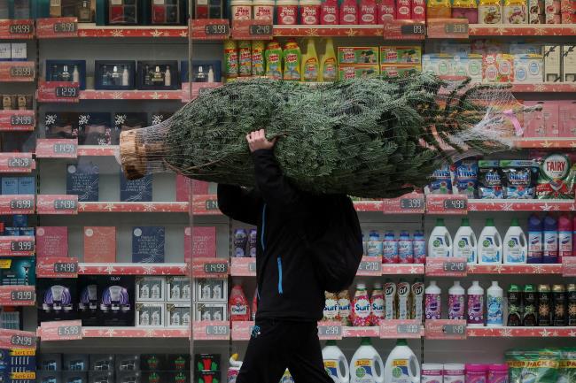 A man carries a Christmas tree amid the coro<em></em>navirus disease (COVID-19) outbreak, in Fulham, London, Britain December 24, 2021. REUTERS/Kevin Coombs   