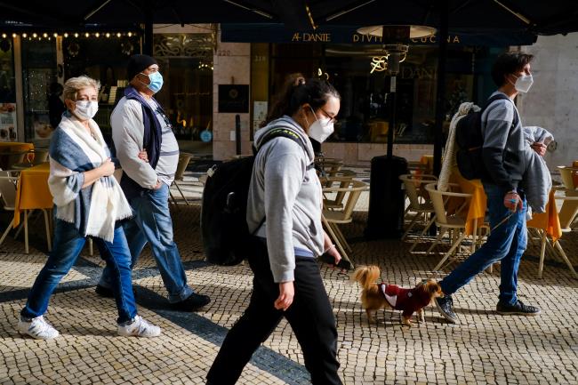 People wearing protective masks walk, moments before a governmental news co<em></em>nference to announce new coro<em></em>navirus disease (COVID-19) restrictions in Lisbon, Portugal, December 21, 2021. REUTERS/Pedro Nunes