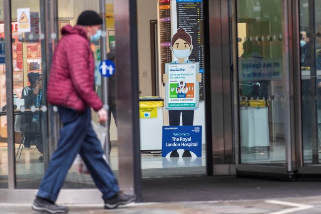 A man wearing a face mask, amid the spread of the coro<em></em>navirus disease (COVID-19), walks past a COVID-19 advisory poster at the Royal Lo<em></em>ndon Hospital, in London, Britain December 31, 2021. REUTERS/May James