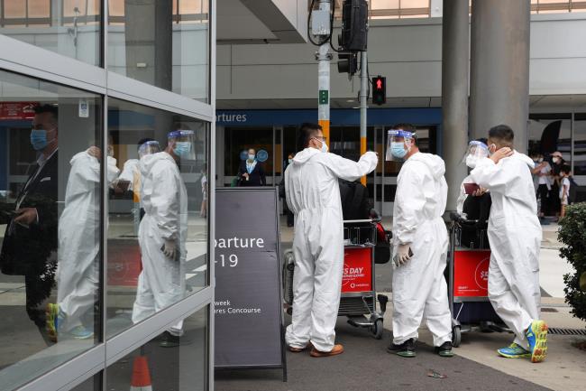 Travellers wear perso<em></em>nal protective equipment outside the internatio<em></em>nal terminal at Sydney Airport, as countries react to the new coro<em></em>navirus Omicron variant amid the coro<em></em>navirus disease (COVID-19) pandemic, in Sydney, Australia, November 29, 2021.  REUTERS/Loren Elliott