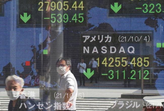 People wearing protective masks amid the coro<em></em>navirus disease (COVID-19) outbreak are reflected on an electro<em></em>nic board displaying Japan's Nikkei and U.S. Nasdaq index outside a brokerage in Tokyo, Japan, October 5, 2021. REUTERS/Kim Kyung-Hoon