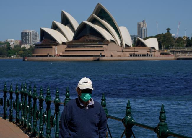 A person wearing a face mask walks along the harbour waterfront across from the Sydney Opera House during a lockdown to curb the spread of coro<em></em>navirus disease (COVID-19) in Sydney, Australia, October 6, 2021. REUTERS/Loren Elliott