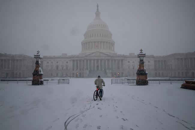 A bicyclist rides along the East Front Plaza during a snow storm on Capitol Hill in Washington, U.S., January 3, 2022. REUTERS/Tom Brenner