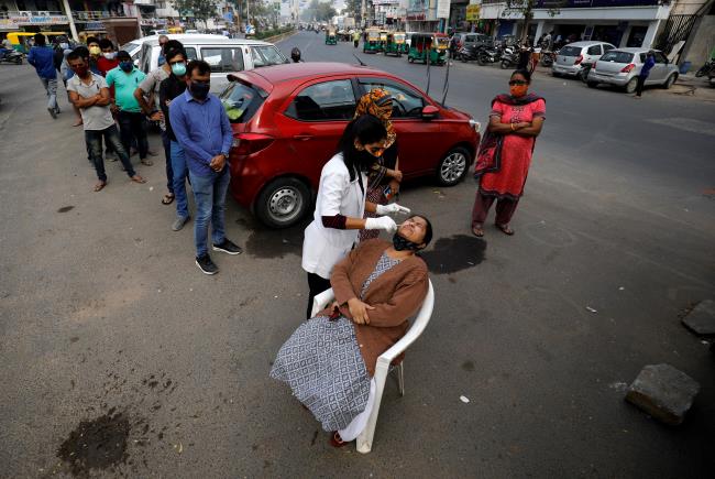 A healthcare worker collects a swab sample from a woman as others wait for their turn during a rapid antigen testing drive for the coro<em></em>navirus disease (COVID-19) at a roadside in Ahmedabad, India, January 5, 2022. REUTERS/Amit Dave