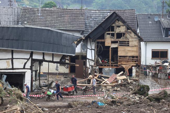 Residents remove rubble among the debris left over by the July 2021 extreme weather and lethal floods of the nearby Ahr river, in Schuld, Germany, July 17, 2021.REUTERS/Wolfgang Rattay