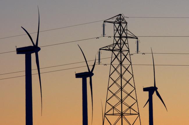 Electricity pylons and wind turbines are silhouetted at the Dun Law West wind farm near Edinburgh, Scotland