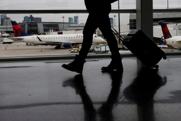 A passenger walks past a Delta Airlines plane at a gate at Logan Internatio<em></em>nal Airport in Boston