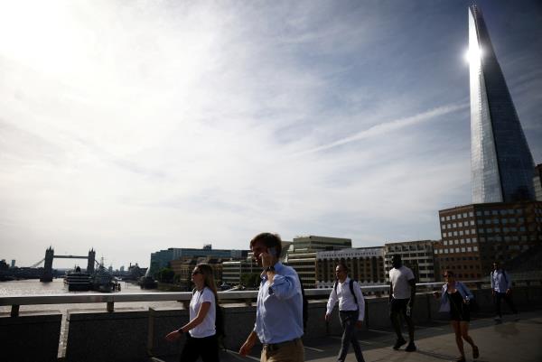 Commuters walk over Lo<em></em>ndon Bridge during warm weather in London