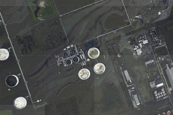 A sheen appears on the flooded property of the Phillips 66 Alliance Refinery