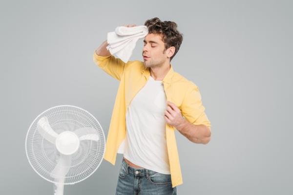 Man looking hot next to a fan