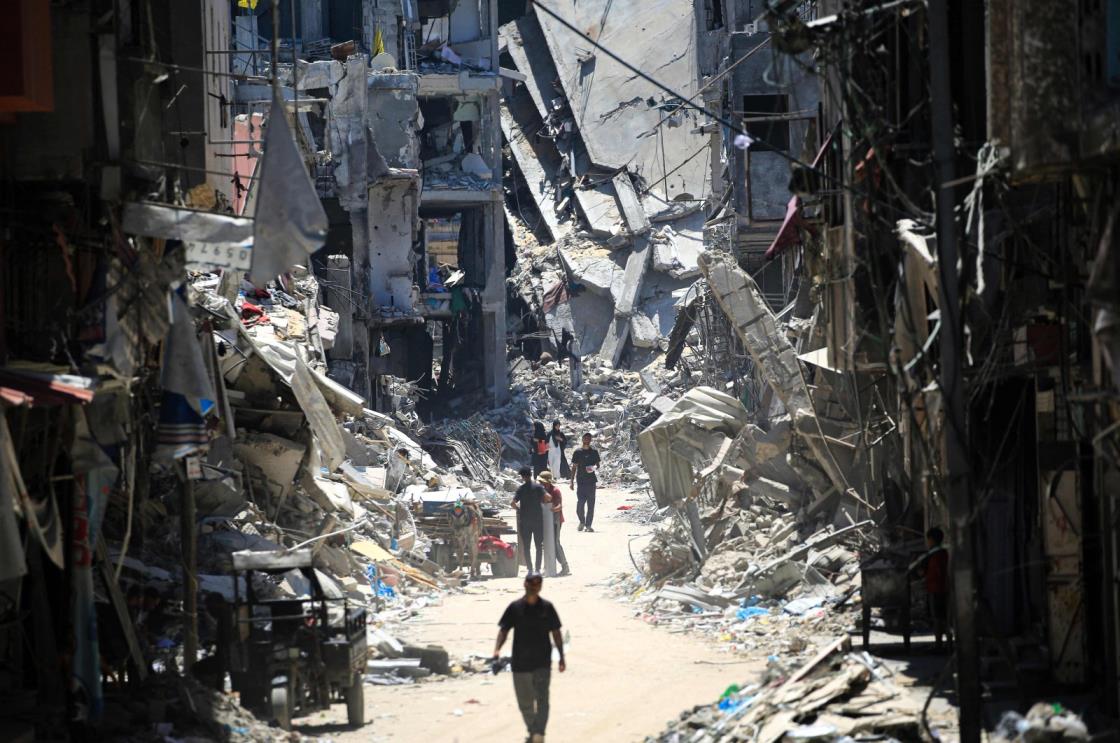 Palestinian men walk along a narrow street past destroyed buildings in Khan Younis, in the southern Gaza Strip, Palestine, June 11, 2024. (AFP Photo)