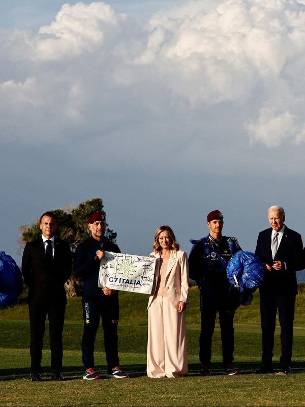 Italy's Prime Minister Giorgia Meloni holds a G7 Italia banner next to the world leaders on the first day of the G7 summit, in Savelletri, Italy.