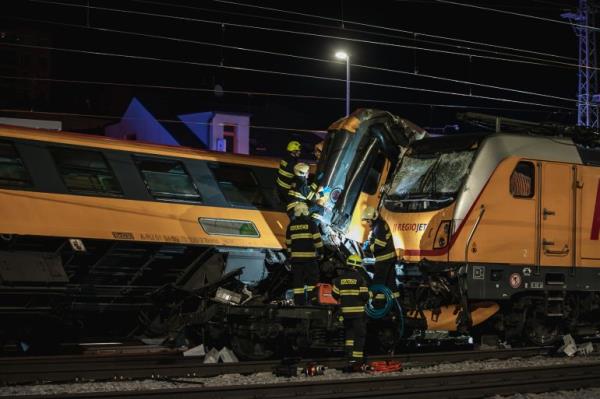 Emergency teams at the site of the train collision. The passenger train is on the left and the carriage has been lifted from the track. The engine of the goods train is on the right.