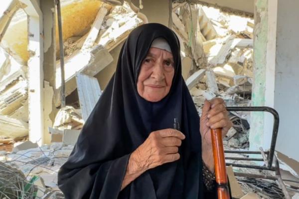 Old lady leaning on a rough stick, surrounded by rubble