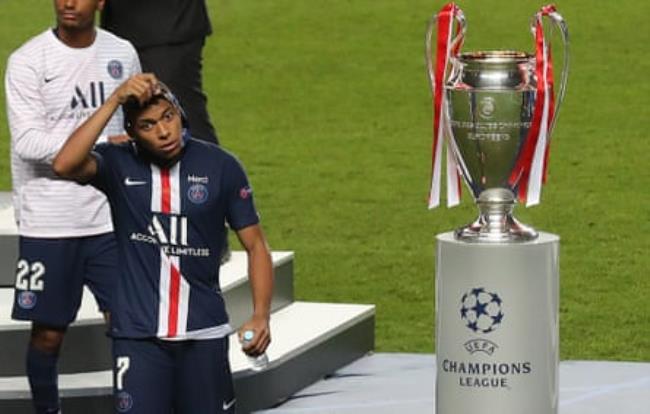 A disappointed Kylian Mbappé walks past the Champions League trophy in 2020