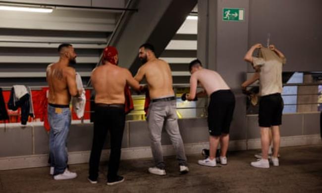Fans wring out their shirts underneath the stands after they got caught in a thunderstorm before the 2024 European Champio<em></em>nship group game between Turkey and Georgia.