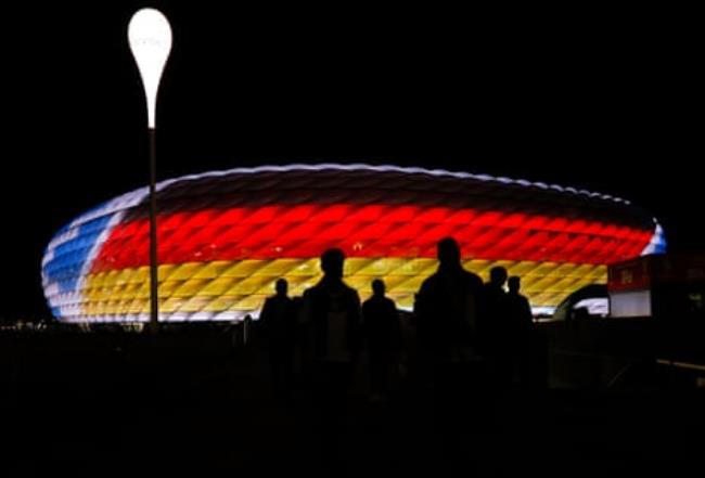 Fans walk away from the Munich Football Arena which is illuminated in the colours of the teams after the 2024 European Champio<em></em>nship group match between Germany and Scotland.