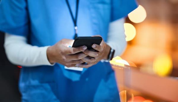 Woman in scrubs texting on phone