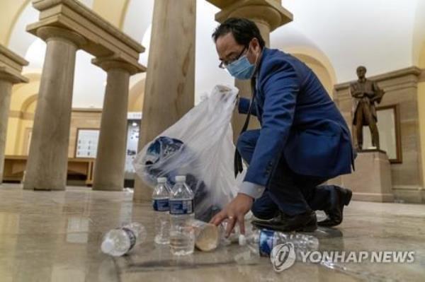 This file photo, released by the Associated Press, shows Rep. Andy Kim picking up trash after the U.S. Capitol in Washington came under attack by rioters on Jan. 6, 2021. (Yonhap)