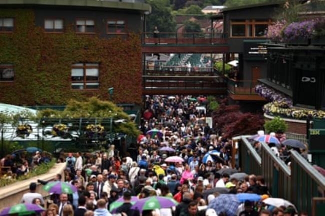 Spectators walk the grounds as rain delays play during day three