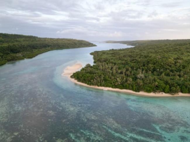 Aerial shot of a channel of water between two beach-fringed forested islands 