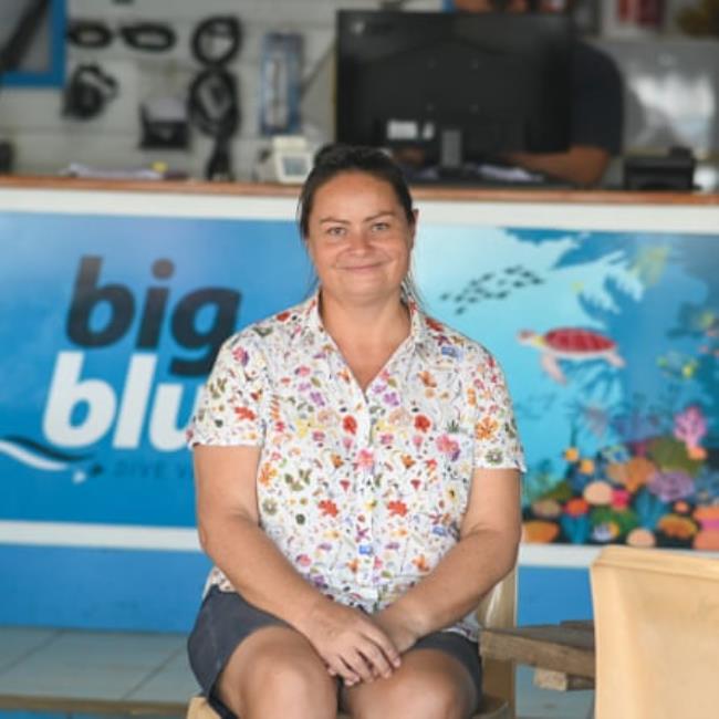 A middle-aged white woman sitting in a scuba diving shop