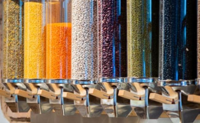 A row of glass dispensers filled with different beans and lentils