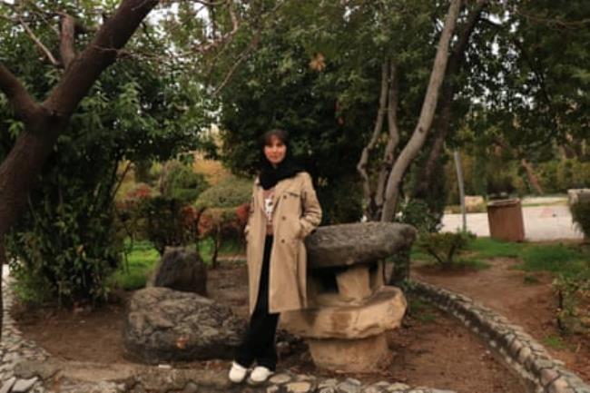 Farzaneh, a journalism student, standing in a wooded garden in Tehran.