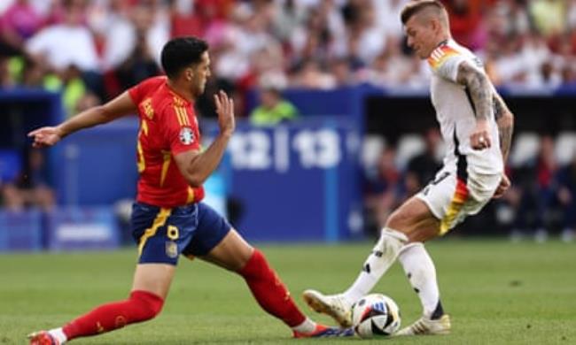 Toni Kroos, playing in his last match before retirement, is hustled off the ball by Mikel Merino.