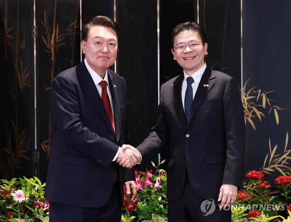 President Yoon Suk Yeol (L) and Singaporean Prime Minister Lawrence Wong shake hands after a joint press co<em></em>nference at the Parliament House in Singapore on Oct. 8, 2024. (Yonhap)