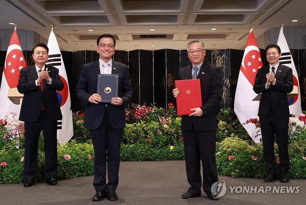 Choi Sang-mok (2nd from L), South Korea's deputy prime minister and finance minister, and his Singaporean counterpart, Gan Kim Yong (2nd from R), pose for a photo after signing a memorandum of understanding on liquefied natural gas cooperation, in the presence of South Korean President Yoon Suk Yeol (L) and Singaporean Prime Minister Lawrence Wong at Parliament House in Singapore on Oct. 8, 2024. (Yonhap)