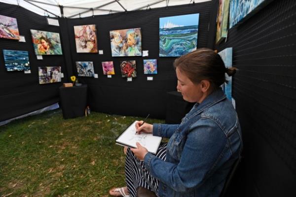 Artist Regina Dell, of Charlestown, Md., works on a sketch at her tent during the 61st Havre de Grace Art Show on the waterfront at Tydings Memorial Parks. (Kenneth K. Lam/Staff)