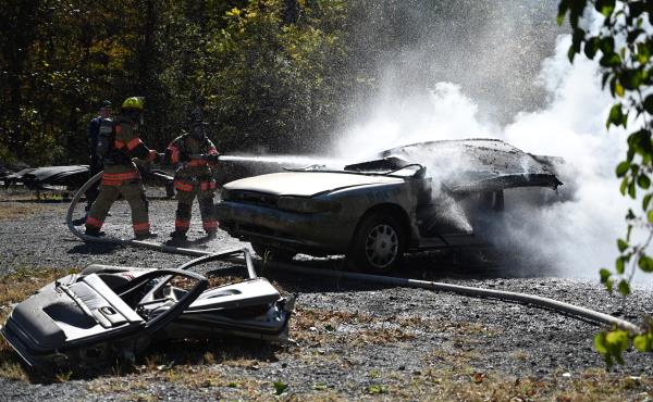 Firefighters Amos Stoltzfus, left, and Brenden Barben work together to put out a fire in a demo<em></em>nstration vehicle during an open house at Whiteford Volunteer Fire Company on Saturday. (Brian Krista/staff photo)