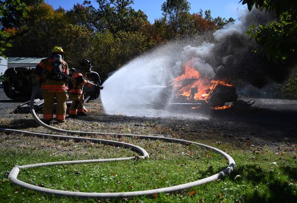 Firefighters Amos Stoltzfus, left, and Brenden Barben work together to put out a fire in a demo<em></em>nstration vehicle during an open house at Whiteford Volunteer Fire Company on Saturday. (Brian Krista/staff photo)