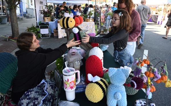 Vendor Caterina Zannino hands one of her crocheted plushies to 8-year-old Natalie Wood of North East during Havre de Grace Fall Fest on Saturday. (Brian Krista/staff photo)