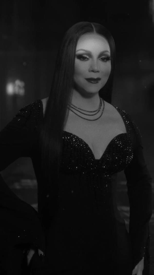 Mariah Carey dressed as Morticia Addams in a black gown with a long black wig