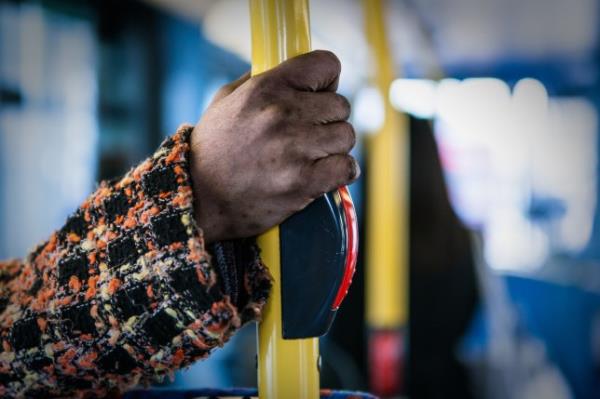 Person holding o<em></em>nto railing on bus