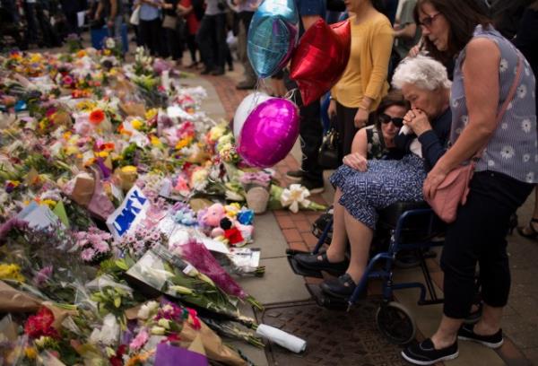 FILE - In this May 24, 2017 file photo women cry after placing flowers in a square in central Manchester, Britain, after the suicide attack at an Ariana Grande co<em></em>ncert that left more than 20 people dead and many more injured, as it ended on Mo<em></em>nday night at the Manchester Arena. (AP Photo/Emilio Morenatti, File)