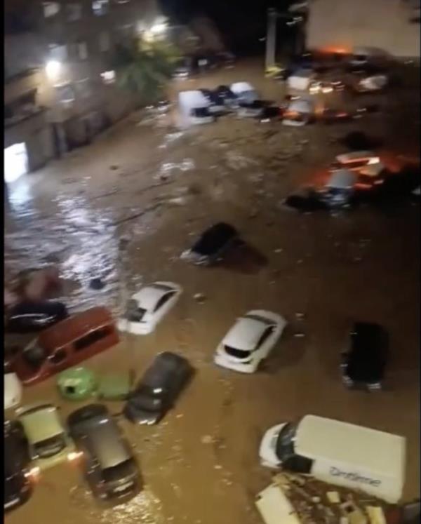 Cars dislodged and surrounded by muddy water in a town.