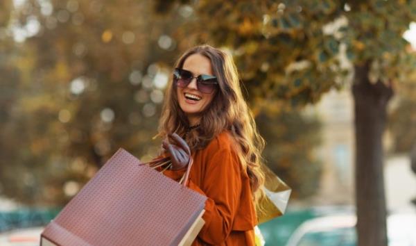 A woman on the street, carrying shopping bags and looking happy