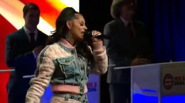 Singer Loomis singing the natio<em></em>nal anthem on TV, in a denim jacket with pink detailing