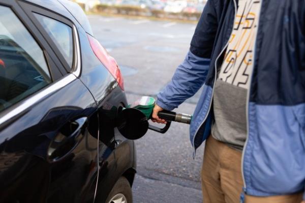 Man's hand holding petrol pump and filling car close up