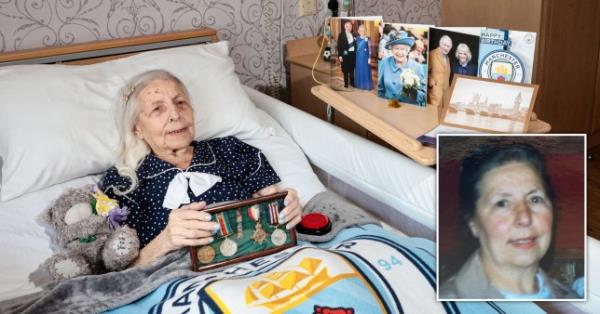 Mary holding medals in a bed beside a teddy and a shelf of birthday cards.