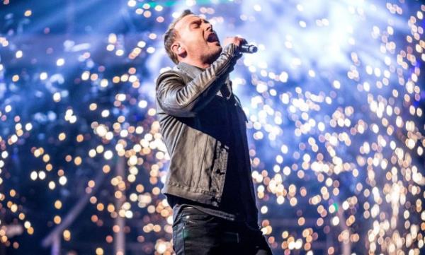 Kevin Simm with lights behind him as he sings on stage, after winning The Voice UK. 