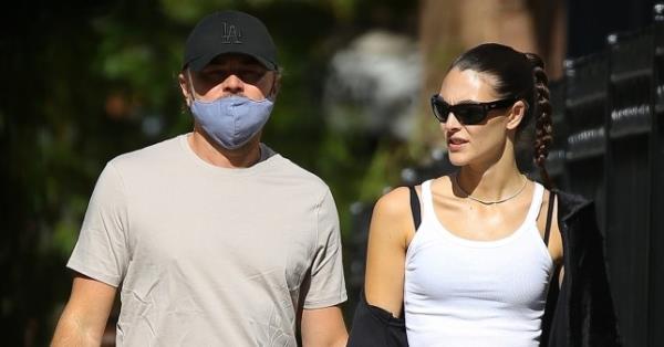 Leo<em></em>nardo DiCaprio and Vittoria Ceretti walking through New York holding hands. Leo<em></em>nardo is wearing beige trousers and shirt with a black cap, while Vittoria is wearing black trousers with a black jacket and a white top